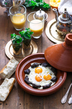 Sunnyside Eggs cooked in a Tajine dish with beef, Moroccan breakfast with juice and mint teaの写真素材