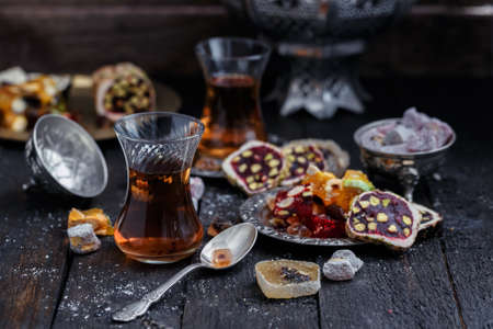 Turkish tea with authentic glass cups. Two cups of turkish tea and sweets on dark wood backgroundの写真素材