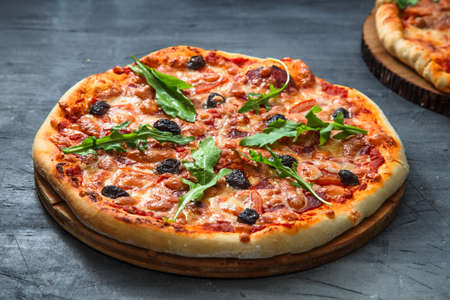 Homemade pizza with tomato, salumi, arugula and olives. Dark backgroundの写真素材