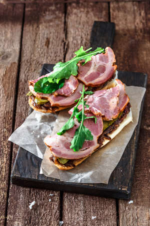 Sandwiches with smoked ham, onion jam, cucubbers and rocket salad on black board, rustic styleの写真素材