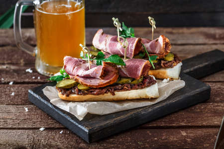 Sandwiches with smoked meat, onion jam and mug of beerの写真素材