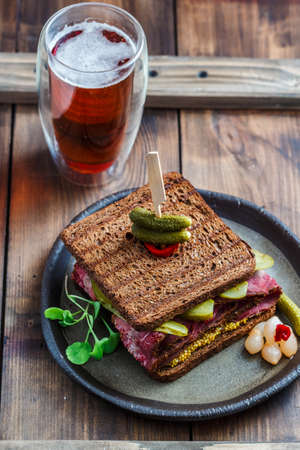 Delicious huge pastrami sandwich with beer and pickleの写真素材