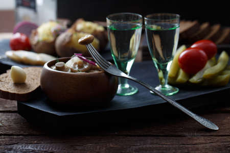 Two shots of vodka and a variety of snacks for it: mushrooms, cucumbers, potato, tomatoesの写真素材