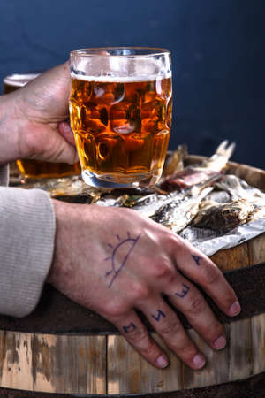 Man drink beer with dried fishes on a wooden barrelの写真素材