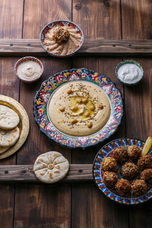 Hummus, chickpea, falafel with tahini, yoghurt and pita in traditional plateの写真素材