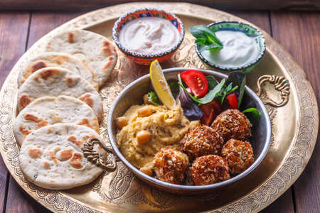 Hummus, falafel, salad and pita in a copper panの写真素材
