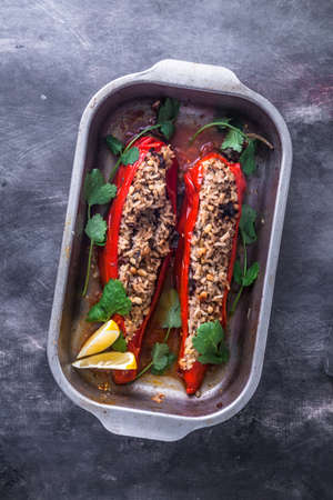 Stuffed paprika peppers in iron cooking pot on dark rustic kitchen table background, top viewの写真素材