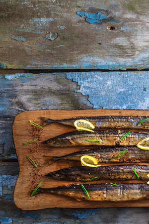 Smoked oceanic saury on wooden cutting board, top view, copy spaceの写真素材