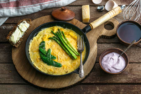 Omelet with green asparagus, pea on frying pan, top view, rustic style.