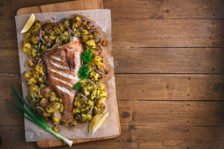 Sea perch or grouper baked with potatoes, top view, copyspace