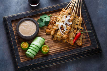 Close view of malaysian chicken skewers - satay or sate ayam with peanut sauce, dark backgroundの写真素材
