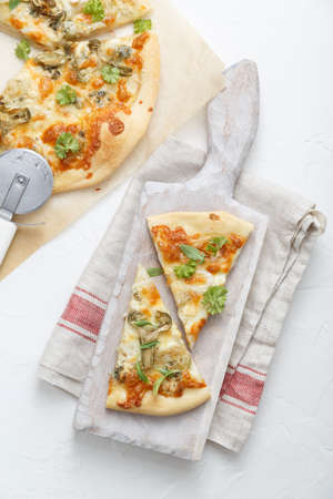 Two pieces of pizza with artichoke on white cutting board