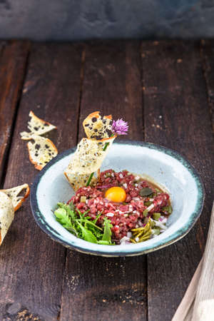 Delicious steak tartare with yolk, capers, green onion and breadの写真素材
