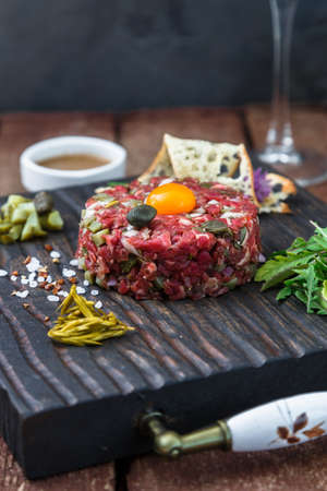 Delicious steak tartare with yolk, capers, green onion and breadの写真素材