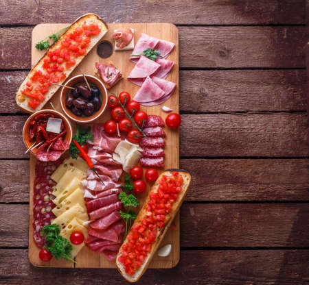Meat and cheese appetizer set for red wine on rustic background, flatlay, copy space.の写真素材