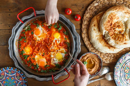Tasty family breakfast with shakshuka, bread and hummus. Rustic styleの写真素材