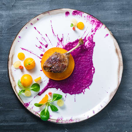 Duck leg confit with cabbage puree and persimon on white plate, restsurant mealの写真素材