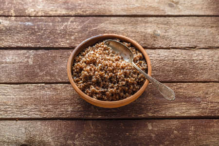 Bowl with cooked buckwheat on old wooden background, copy space.の写真素材