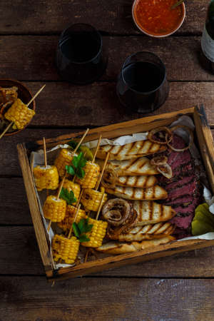 Smoked pastrami slices with grilled corn and wine.