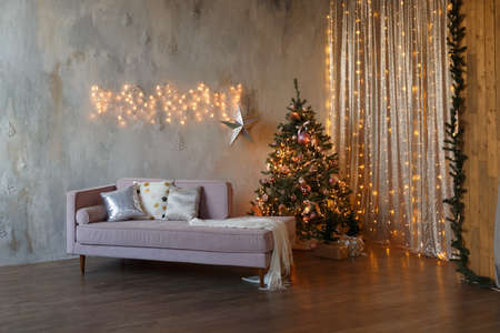 Dark loft living room decorated for Christmas with tree and lightsの写真素材