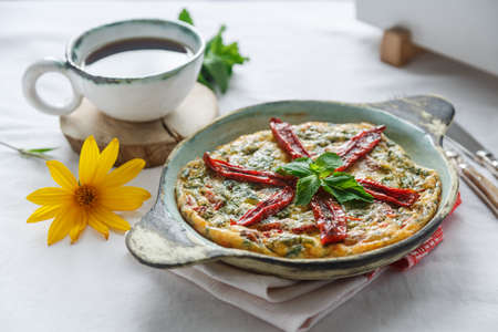 Traditional fritatta with dry tomatoes in a cast iron pan. White background, copy spaceの写真素材