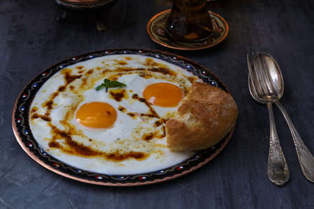 Cilbir, eggs in yogurt with spiced butter and herbs, served with bread and tea, turkish cuisine, copy spaceの写真素材