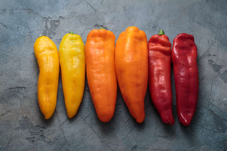 Box of ripe color peppers on wooden background.