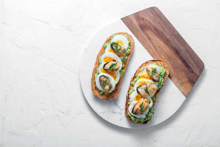 Smoked mussels and avocado toasts, white background, copy space