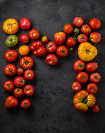 Letter M made with ripe tomatoes on a black background, creative flat lay healthy food conceptの写真素材