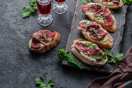 Bruschetta with roast beef, mayo and greens leaves on wooden board.の写真素材