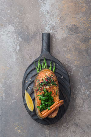 Fried salmon steak with vegetables on wooden boardの写真素材