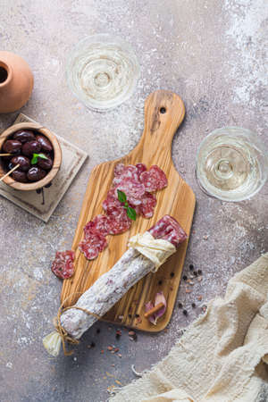 Italian salami on wooden board with cheese and olives, copy space