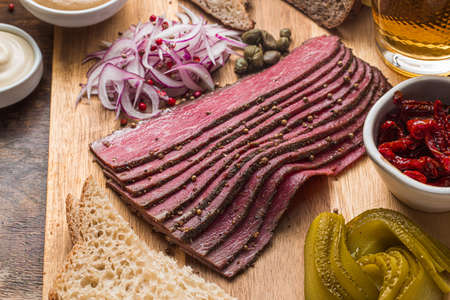 Sliced Deli Pastrami on wooden board, flat lay.の写真素材
