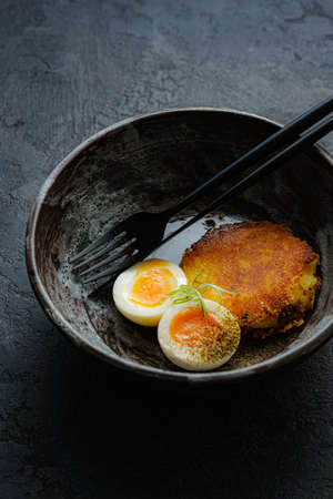Delicious fried hot potato croquet with soft-boiled egg close-up in a bowl on the tableの写真素材