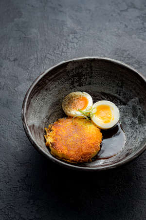 Delicious fried hot potato croquet with soft-boiled egg close-up in a bowl on the tableの写真素材
