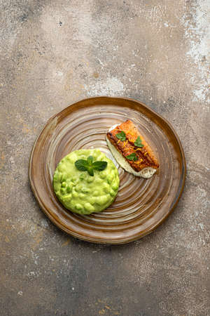 Pan seared white fish fillet with edamame puree on rustic backgroundの写真素材
