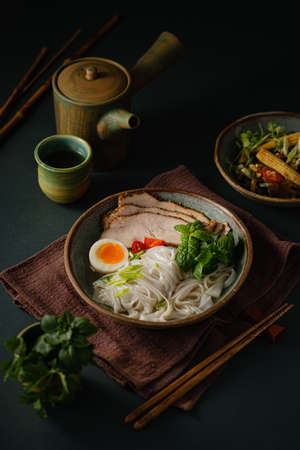 Asian noodle soup on table, ramen with pork, vegetables and egg in a bowl. Copy spaceの写真素材