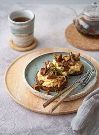 Cozy breakfast Scrambled eggs with chanterelle on buns with tea, copy spaceの写真素材