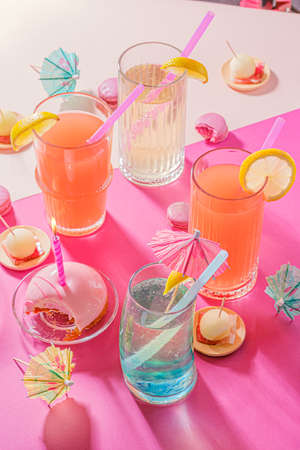 Bright birthday party background with cocktails and candy. Colored holiday accessories on pink...
