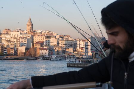 Istanbul, Turkey - Jan 10, 2020: Fishermen on the Galata Bridge, in Eminonu district , Galata Bridge is in background Beyoglu district, Istanbul. Turkeyのeditorial素材