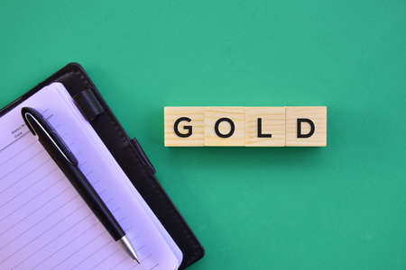 'Gold' word on wood block with green background flat lay concept.の写真素材