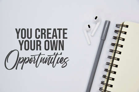 'You create your own opportunities' quote on white background with notebook, pen and earbuds...