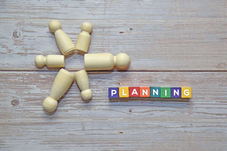 Wooden dolls on top of wooden blocks with PLANNING text beside. Business concept.