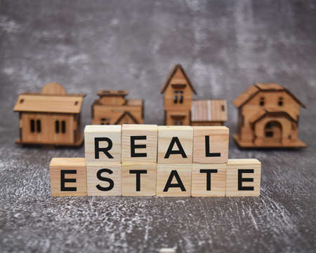 Real estate text on wooden blocks with blur house models background. Selective focus image.の写真素材
