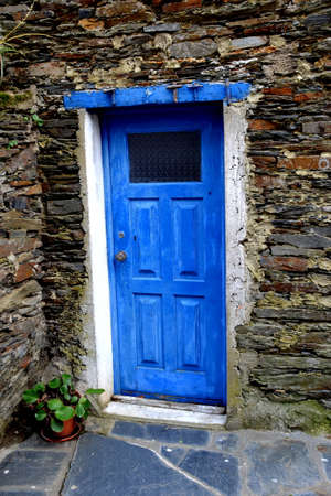 Rustic hand-hewn wood door set into a stone wall built from schist in Piodão, made of shale rocks stack, one of Portugal's schist villages in the Aldeias do Xisto.の写真素材
