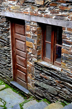Rustic hand-hewn wood door set into a stone wall built from schist in Piodão, made of shale rocks stack, one of Portugal's schist villages in the Aldeias do Xisto.の写真素材