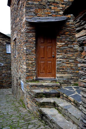Rustic hand-hewn wood door set into a stone wall built from schist in Piodão, made of shale rocks stack, one of Portugal's schist villages in the Aldeias do Xisto.の写真素材