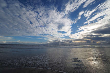 Sunset over the beach of Playa El Coco, Nicaragua, with a colorful cloudscape reflected in the coastal water.の写真素材