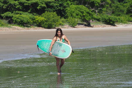Playa Hermosa, Nicaragua 06-13-2017 Young woman surfs on Playa Hermosa on a sunny summer day.