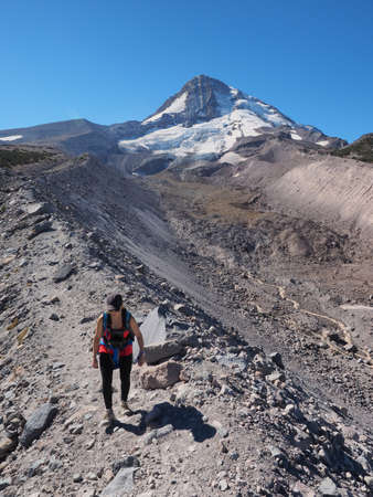 Woman hiking on the Timberline Trail on Mount Hood, Oregon, enjoying views of the volcanos north...